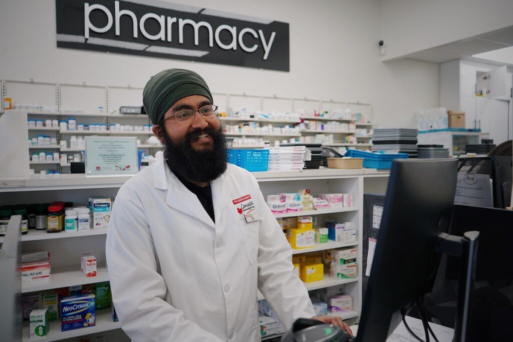A community pharmacist smiling at the counter of a modern UK pharmacy