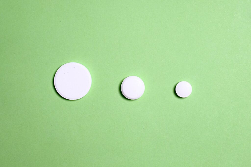 White weight-loss medication tablets of varying sizes on a green surface