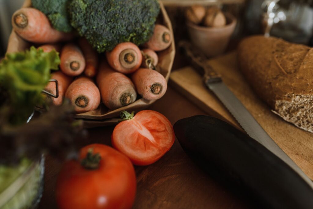 A wooden table laid with fresh vegetables and bread, representing a balanced diet