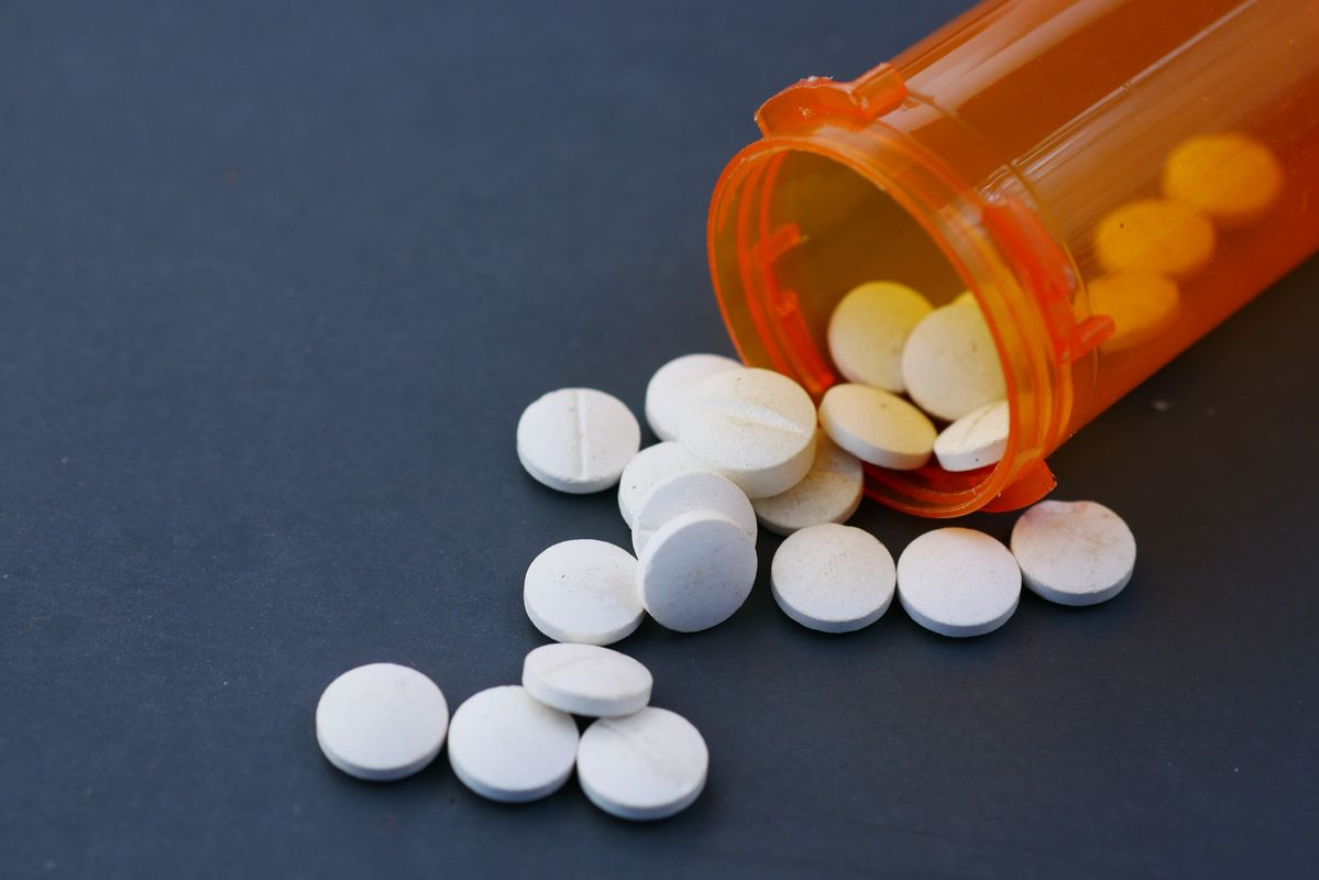 White prescription tablets beside an orange medicine bottle